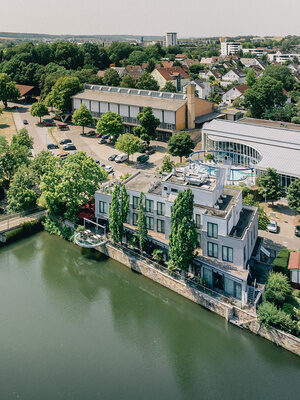 Luftaufnahme des Hotels Eberhards am Wasser direkt am Fluss mit Fußgängerbrücke
