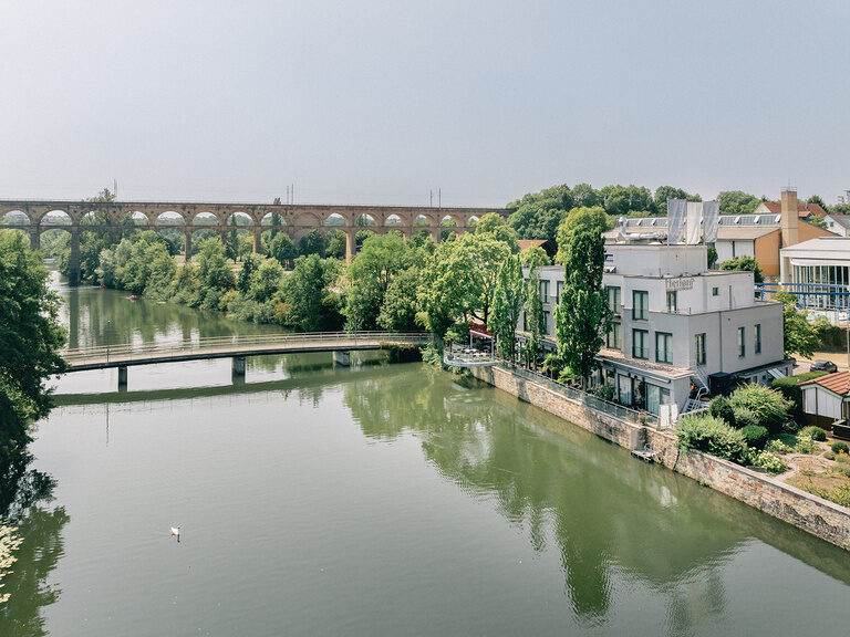 Eberhards am Wasser direkt am Fluss mit historischem Viadukt im Hintergrund.