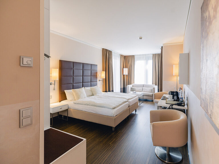 Helles Doppelzimmer mit großem Bett, Sitzecke und moderner Einrichtung