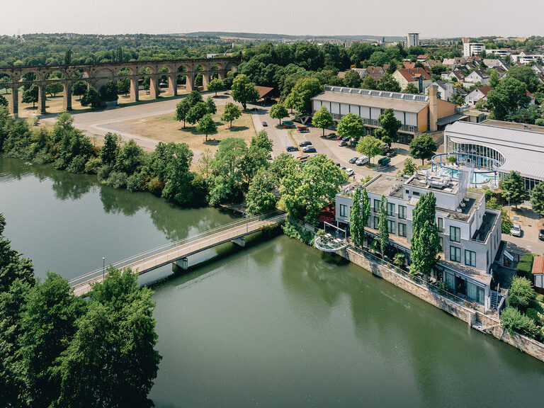 Luftaufnahme des Hotels Eberhards am Wasser direkt am Fluss mit Fußgängerbrücke
